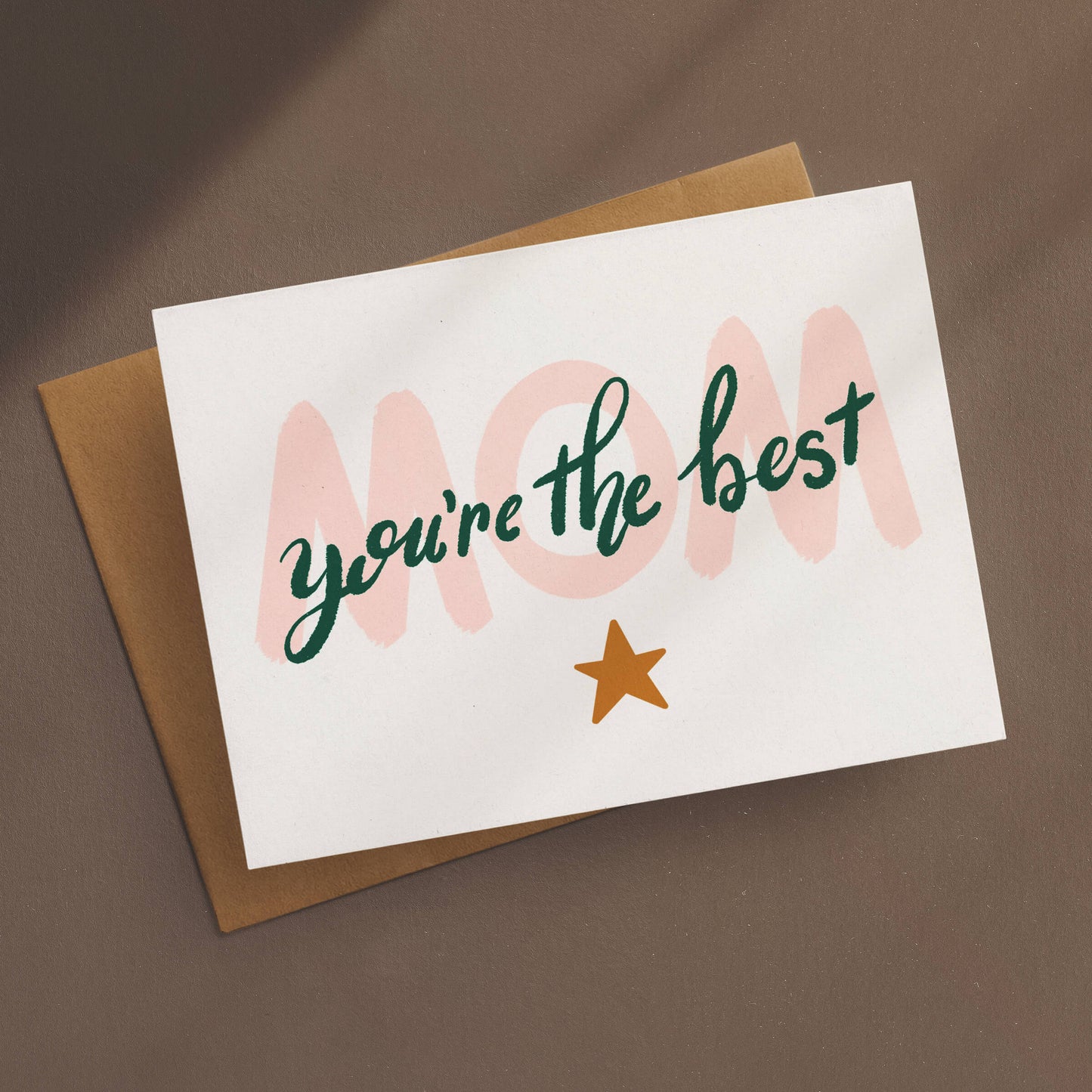 Greeting card with a charming design that features a large, light pink “Mom” elegantly overlaid with dark green lettering that proclaims “you’re the best,” all set against a soft white background. A little gold star shines below, adding a touch of sparkle to your message.